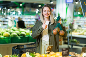 年轻的女人选择选择生态袋蔬菜水果橙子超市
