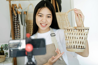 关闭年轻的亚洲女商人时尚博主显示<strong>编织篮子</strong>产品微笑