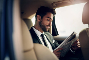 阅读报纸早期早....自信年轻的商人阅读报纸坐着后座车