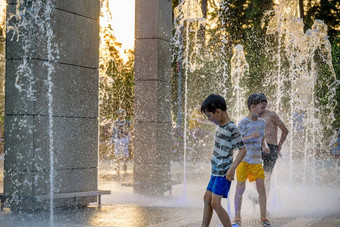 男孩跳水喷泉孩子们玩城市喷泉热夏天一天快乐朋友有趣的喷泉夏<strong>天天</strong>气友谊生活方式假期