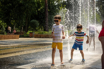男孩有趣的水喷泉孩子玩城市喷泉热夏天一天快乐孩子们有趣的喷泉夏天天气活跃的休闲生活方式假期