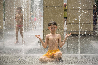 男孩冥想水喷泉找到Zen孩子玩城市喷泉热夏天一天快乐孩子们有趣的喷泉夏<strong>天天</strong>气活跃的休闲生活方式假期