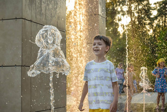 男孩有趣的水喷泉孩子玩城市喷泉热夏天一天快乐孩子们有趣的喷泉夏<strong>天天</strong>气活跃的休闲生活方式假期