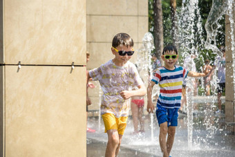 男孩有趣的水喷泉孩子玩城市喷泉热夏天一天快乐孩子们有趣的喷泉夏天天气活跃的休闲生活方式假期