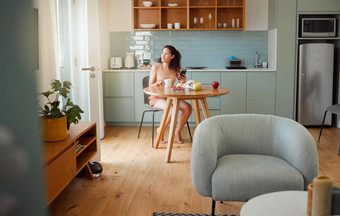 女人电话思考早餐的想法健康的零食喝咖啡早....时尚的厨房放松女孩怀旧现代公寓室内设计