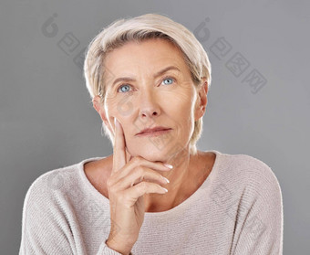 成熟的思考女人触碰脸孤立的灰色工作室背景复制空间反老化护肤品化妆品产品高级感觉皮肤皱纹头像