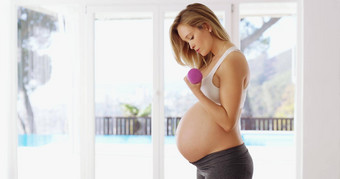 建筑强度婴儿有吸引力的年轻的怀孕了女人工作哑铃