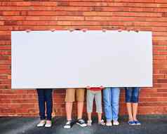 我们保存空间集团年轻的孩子们持有空白标志砖墙