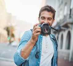 摄影使意识到周围的环境年轻的男人。采取照片探索外国城市
