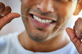 用牙线清洁牙齿微笑太棒了快乐年轻的男人。用牙线清洁牙齿牙齿首页