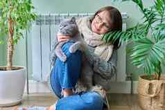中年女人毛衣猫坐着加热散热器