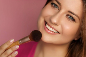 美丽的年轻的女人应用化妆品粉产品化妆竹子刷美化妆<strong>护肤品</strong>化妆品模型脸肖像粉红色的背景