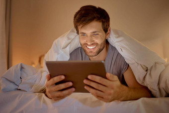 快乐男人。放松床上数字平板电脑看电影系列在线社会媒体视频应用程序浏览互联网新闻技术无线设备卧室首页