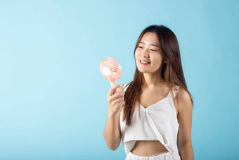 亚洲美年轻的女人持有粉红色的可移植的电迷你<strong>风扇</strong>脸