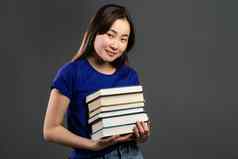 亚洲学生灰色背景工作室持有堆栈大学书图书馆女人微笑快乐研究生