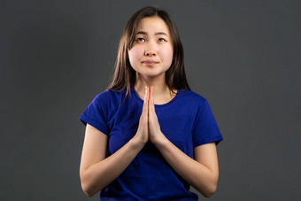可爱的亚洲年轻的女孩祈祷灰色背景朝鲜文女人眼镜乞讨