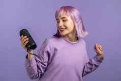 不寻常的女人紫罗兰色的发型听音乐无线可移植的演讲者现代声音系统年轻的女孩跳舞享受工作室背景