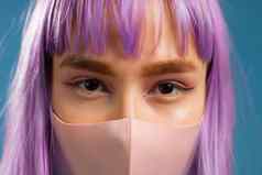 年轻的赶时髦的人女人保护面具特写镜头肖像时尚模型染色紫罗兰色的发型流感大流行科维德概念