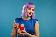 兴奋时尚的女人紫罗兰色的头发收到了礼物盒子弓快乐受宠若惊注意女孩微笑现在蓝色的背景工作室肖像