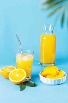 玻璃橙色汁橙色芒果片蓝色的背景