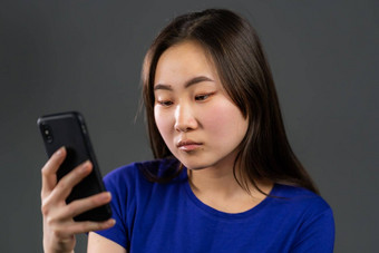 亚洲年轻的女孩短信发短信应用程序智能手机漂亮的女人冲浪互联网移动电话灰色工作室
