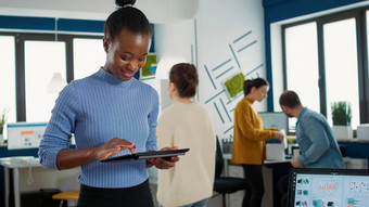 肖像非洲美国女人站忙办公室挑选平板电脑业务企业资源计划软件微笑
