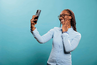 快乐自信非洲美国女人现代触屏智能手机采取自拍照片