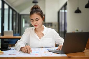 美丽的年轻的女经济学家<strong>专业</strong>女商人分析<strong>金融</strong>图图表<strong>数据</strong>移动PC办公室桌子上