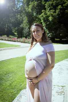 月怀孕了女人粉红色的透明的衣服持有肚子
