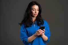 成熟的女人短信发短信应用程序智能手机漂亮的成人夫人冲浪互联网移动电话灰色工作室肖像