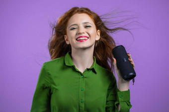 女人听音乐无线可移植的演讲者现代声音系统夫人跳舞享受紫罗兰色的工作室背景移动节奏音乐