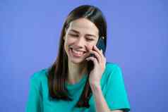 年轻的女人说话微笑电话女孩持有聪明的电话紫罗兰色的工作室背景