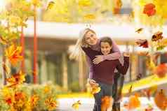 快乐家庭秋天走妈妈。女儿走公园享受美丽的秋天自然