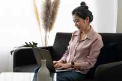 微笑亚洲年轻的女人工作移动PC首页办公室年轻的亚洲学生电脑远程研究虚拟培训电子学习看在线教育网络研讨会房子