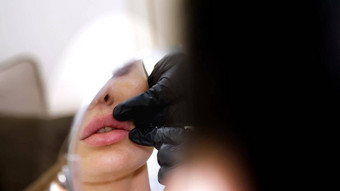 医疗办公室美丽的女人镜子医生探针病人的嘴唇注射透明质酸酸嘴唇修正形状嘴唇