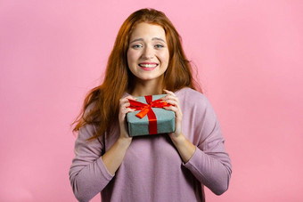 兴奋女人收到了礼物盒子弓快乐受宠若惊注意女孩微笑现在粉红色的背景工作室肖像