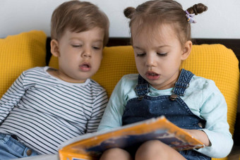 预播蹒跚学步的孩子们读大有趣的书仙女故事黄色的床上兄弟姐妹双胞胎读者有趣的快乐孩子检疫首页友谊家庭教育概念