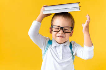 有趣的学前教育孩子男孩眼镜书头袋黄色的背景复制空间快乐微笑孩子回来学校幼儿园成功动机赢家天才超级英雄概念