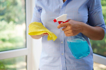 特写镜头家庭主妇喷涂洗涤剂黄色的布洗窗户阳台春天清洁概念
