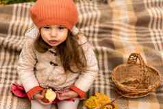 关闭肖像可爱的学前教育小女孩橙色贝雷帽黄色的下降叶子吃红色的苹果相机冷天气秋天公园童年家庭母亲秋天概念