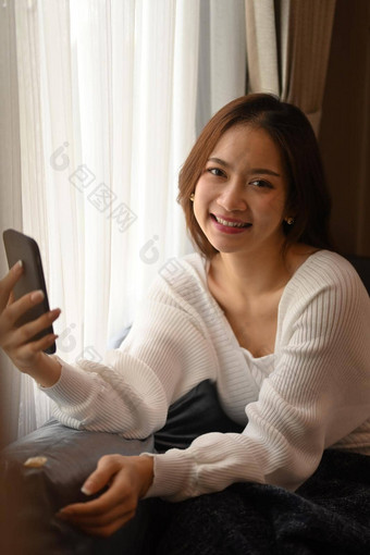 快乐的年轻的女人休息沙发上聪明的电话冬天秋天周末