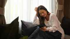 微笑年轻的女人放松舒适的沙发上享受聊天在线朋友聪明的电话
