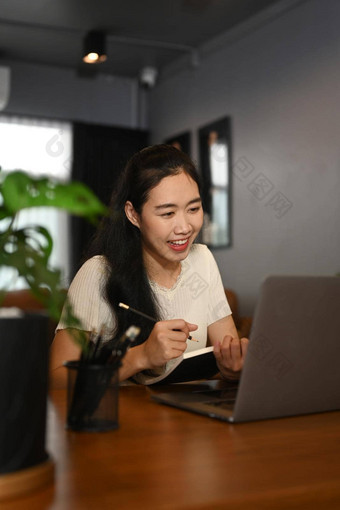 迷人的女自由职业者阅读在线新闻检查电子邮件移动PC坐着首页办公室