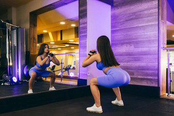 年轻的美丽的体育女人健身房练习<strong>下蹲</strong>前面镜子体育统一的