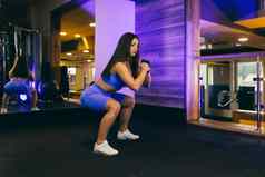 年轻的美丽的体育女人火车健身房练习哑铃健身运动服装