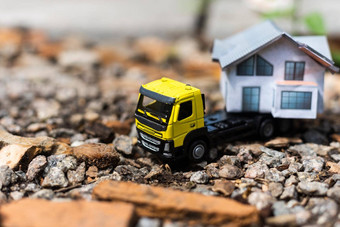特写镜头小玩具卡车树树桩携带微型房子模型前模糊森林背景前面视图农村搬迁服务概念