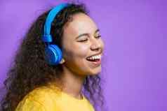 有吸引力的女人跳舞无线耳机紫罗兰色的工作室背景可爱的女孩跳舞微笑音乐广播幸福自由青年概念