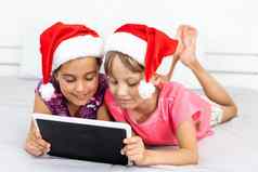 圣诞节x-mas冬天幸福概念可爱的卷曲的女孩玩平板电脑