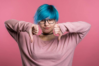 年轻的漂亮的女人蓝色的头发站粉红色的工作室背景表达不满显示拇指手势相机肖像女孩标志不喜欢