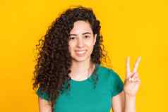 漂亮的女孩卷曲的发型黄色的背景美丽的肖像女人绿色t恤微笑相机拉丁拉美裔比赛年轻的模型